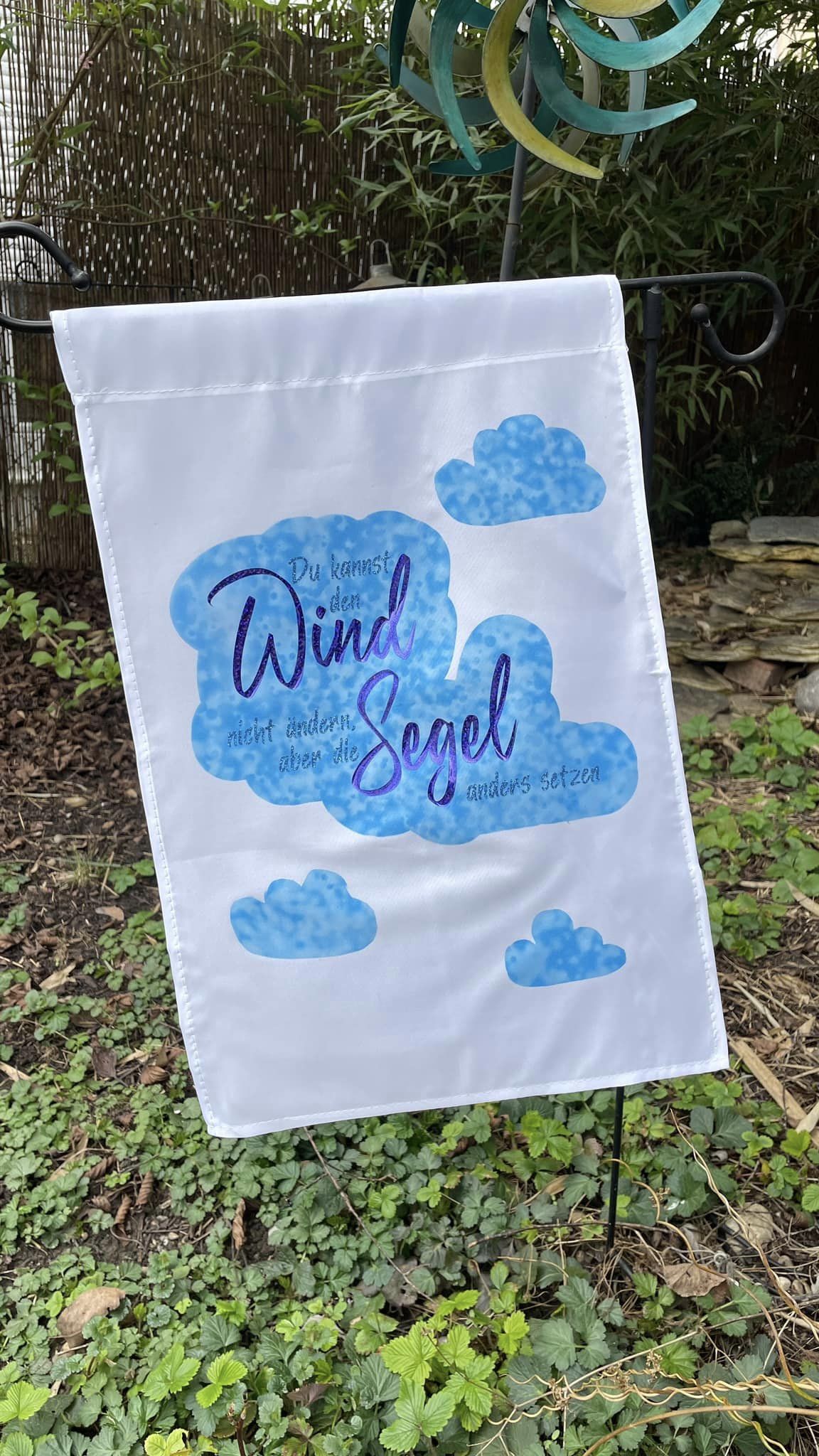 Bunte Gartenflagge mit dem Spruch "Du kannst den Wind nicht ändern, aber die Segel anders setzen" von easy-sticks, ideal für kreative Projekte mit der Plotterdatei.