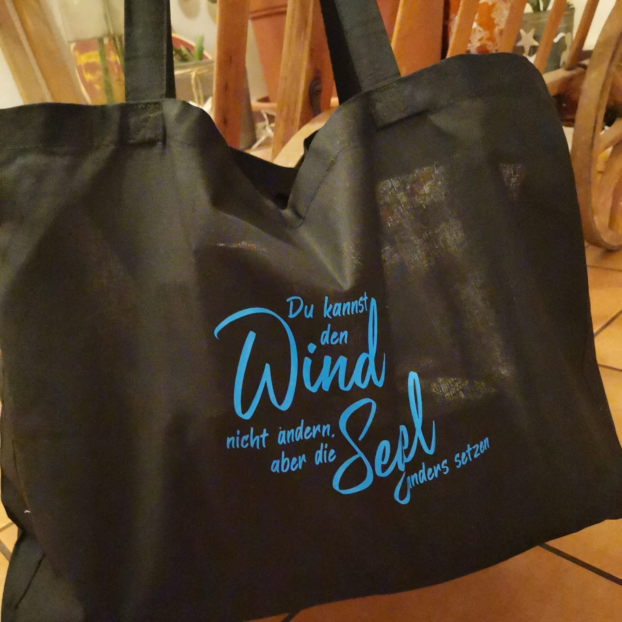 Schwarze Tragetasche mit dem inspirierenden Spruch "Du kannst den Wind nicht ändern, aber die Segel anders setzen" von easy-sticks, perfekt für DIY-Projekte mit der Plotterdatei.