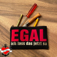 Schwarze Kosmetiktasche voller Werkzeuge, verziert mit dem Aufdruck 'EGAL ich lass das jetzt so', kreiert mit der Plotterdatei von easy-sticks für kreative DIY-Projekte.