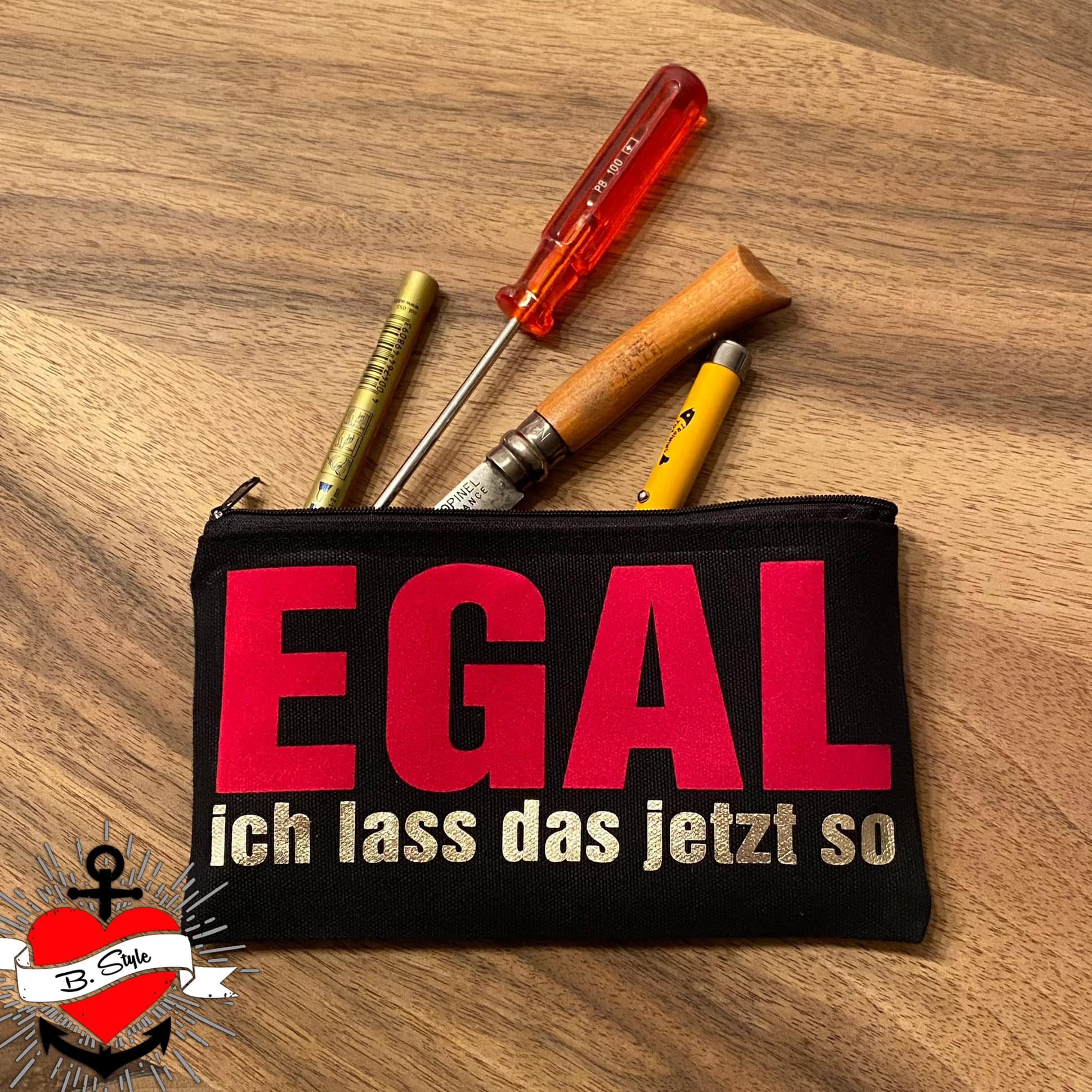 Schwarze Kosmetiktasche voller Werkzeuge, verziert mit dem Aufdruck 'EGAL ich lass das jetzt so', kreiert mit der Plotterdatei von easy-sticks für kreative DIY-Projekte.
