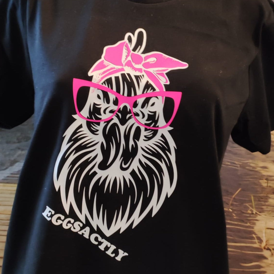 Schwarzes T-Shirt mit kreativem Hühner-Motiv und der Aufschrift 'EGGSACTLY' von easy-sticks, präsentiert auf einer Büste.