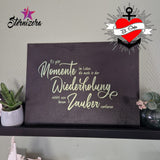 Wandbild mit dem Spruch "Es gibt Momente im Leben die auch in der Wiederholung nichts von ihrem Zauber verlieren" von easy-sticks, präsentiert auf einem Regal neben einer dekorativen Pflanze.