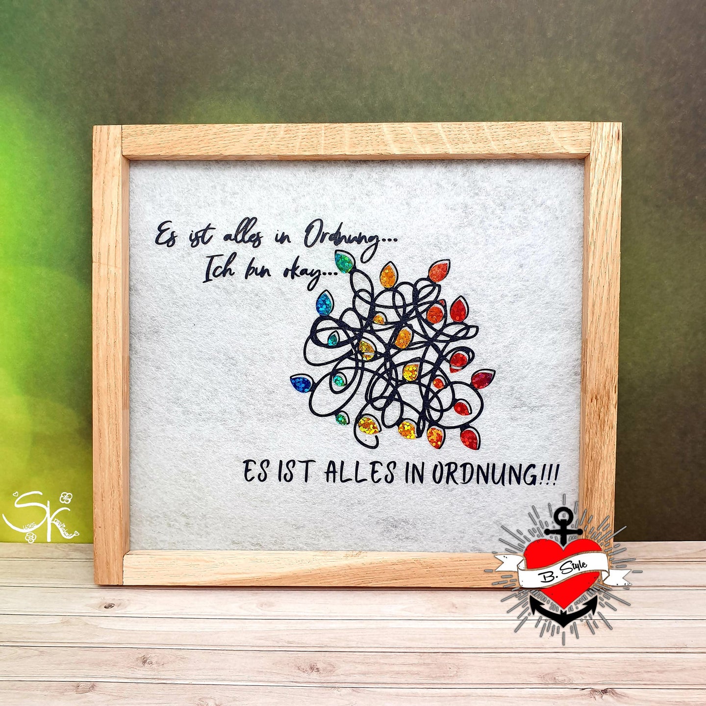 Gestaltetes Bild mit Holzrahmen, das die Plotterdatei "Es ist alles in Ordnung...Ich bin ok...ES IST ALLES IN ORDNUNG" von easy-sticks zeigt, umgeben von bunten Dekorationselementen.