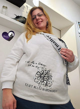Frau trägt ein weißes Sweatshirt mit dem Design „Es ist alles in Ordnung...Ich bin ok...ES IST ALLES IN ORDNUNG“ von easy-sticks, zeigt ein modernes und gemütliches Outfit.