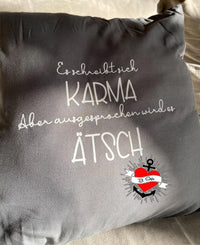 Ein Kissen mit dem Aufdruck "Es schreibt sich Karma Aber ausgesprochen wird es Ätsch" von easy-sticks, ideal für personalisierte Wohnaccessoires und kreative Ideen.