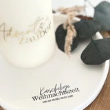 Rub on UV Sticker randlos Zuhause A5 von easy-sticks, gezeigt auf einer eleganten Kerze mit dem Schriftzug 'Advent zauber' und minimalistischer Dekoration.