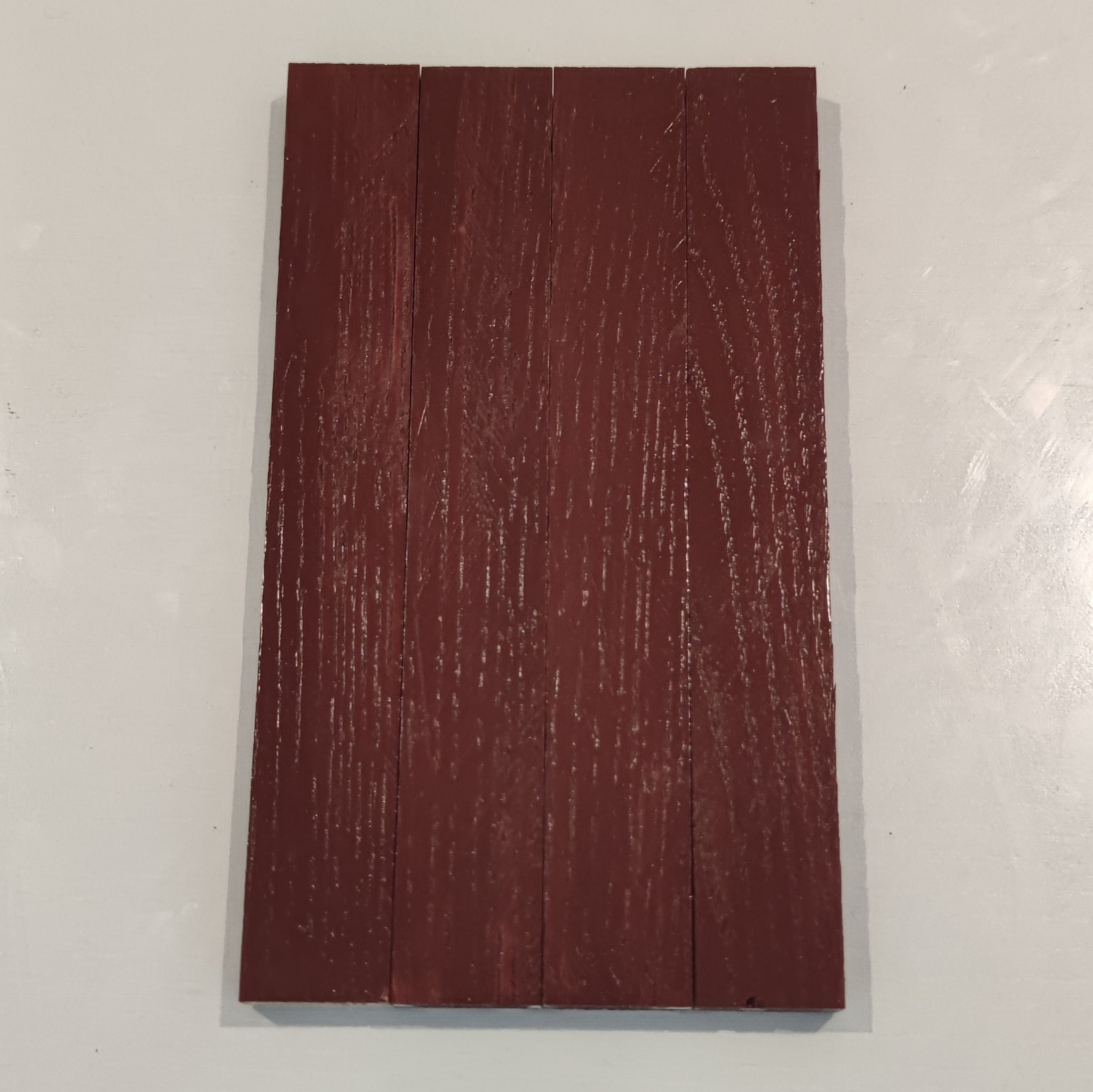 Detailaufnahme einer mit Easy-Sticks Color Holzfarbe Schweden Rot gestrichenen Holzfläche, die ihre reichhaltige Farbe und Struktur zeigt.