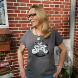Lächelnde Frau in einem grauen T-Shirt mit 'Free Spirit' Aufdruck, präsentiert von easy-sticks, perfekt für kreative Ausdrucksformen.