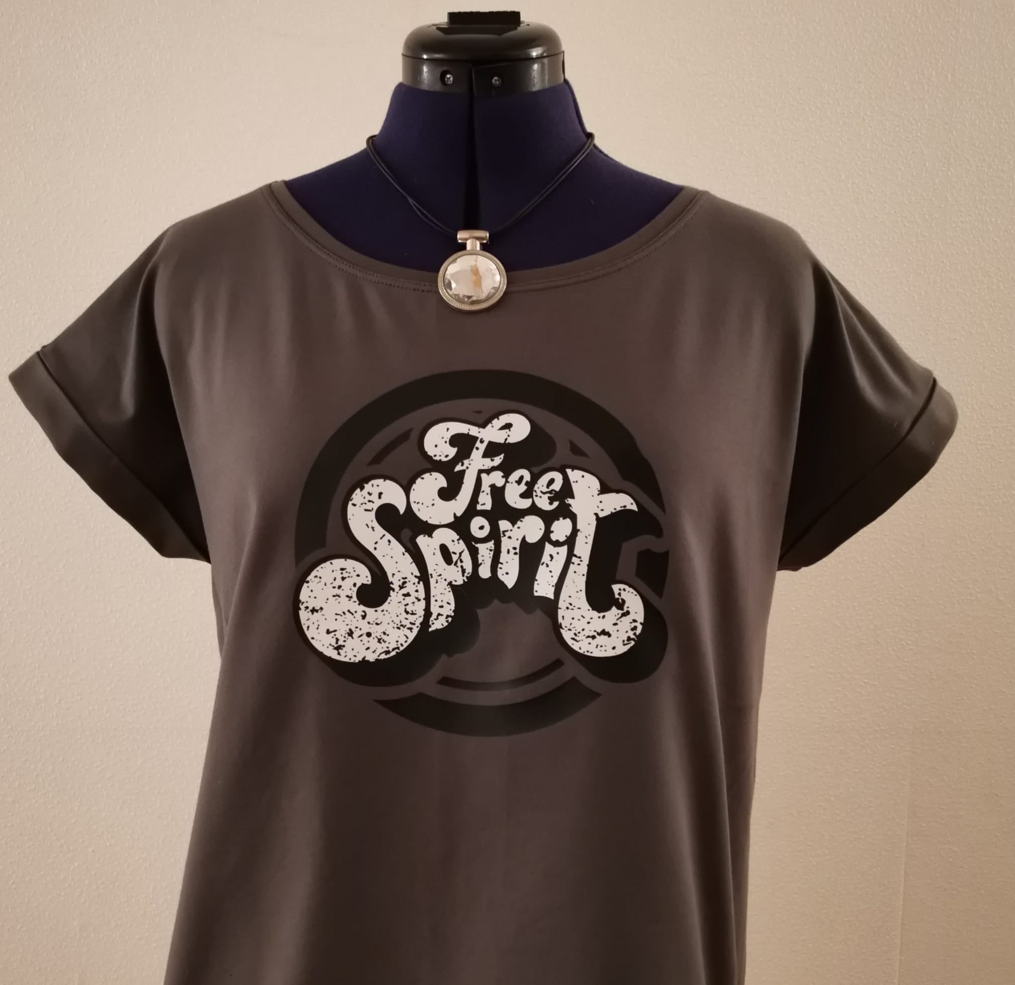 Modisches graues T-Shirt mit dem 'Free Spirit' Logo an einer Schneiderpuppe, designt von easy-sticks, perfekt für kreative Outfits.