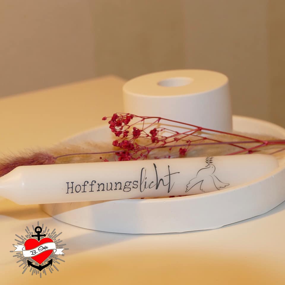 Eine elegante Friedenskerze 'Hoffnungslicht', platziert auf einem minimalistischen, weißen Untergrund, umgeben von dekorativen Zweigen und floralen Akzenten. Lass deiner Kreativität mit der Friedenskerze PDF Datei und Plotterdatei von easy-sticks freien Lauf.