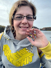 Portrait einer Frau, die ein graues Sweatshirt mit dem Aufdruck 'FUCK THIS SHIT' von easy-sticks trägt und eine kreative Atmosphäre ausstrahlt.