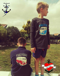 Zwei Kinder in modischen T-Shirts mit dem Motiv "Fuel for the soul" von easy-sticks, stehen outdoor und posieren, einer trägt ein blaues Shirt, der andere ein schwarzes.