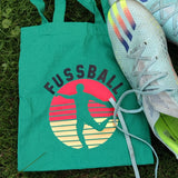 Fussball Plotterdatei von easy-sticks, bunten Aufdruck auf einer grünen Tragetasche neben Fußballschuhen, ideal für Sportbegeisterte.