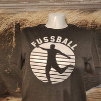 Fussball Plotterdatei von easy-sticks, stilvoller Druck auf einem grauen T-Shirt mit einer dynamischen Silhouette eines Spielers und dem Wort 'FUSSBALL'.