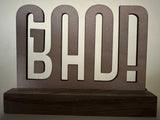 Holzdesign mit dem Schriftzug 'BAD!', kunstvoll verarbeitet und ideal für einzigartige Projekte mit der Plotterdatei 'Good Bad' von easy-sticks.