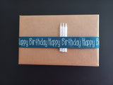 Kreativ verpacktes Geburtstagsgeschenk mit einer blauen Schleife, die "Happy Birthday" aufgedruckt hat, ideal für DIY-Projekte mit der Geburtstagsgrüße Datei zum Plotten und Drucken von easy-sticks.