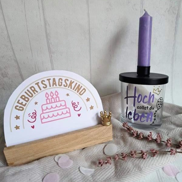 Dekorative Geburtstagsaccessoires von easy-sticks: Tischdekoration mit dem Spruch 'Geburtstagskind' und eine Kerze mit 'Hoch sollst du leben'.