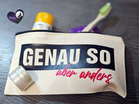 Praktisches Kosmetiktäschchen mit der Aufschrift "Genauso aber anders" von easy-sticks, gefüllt mit Pflegeprodukten und Zahnbürste, perfekt für unterwegs.