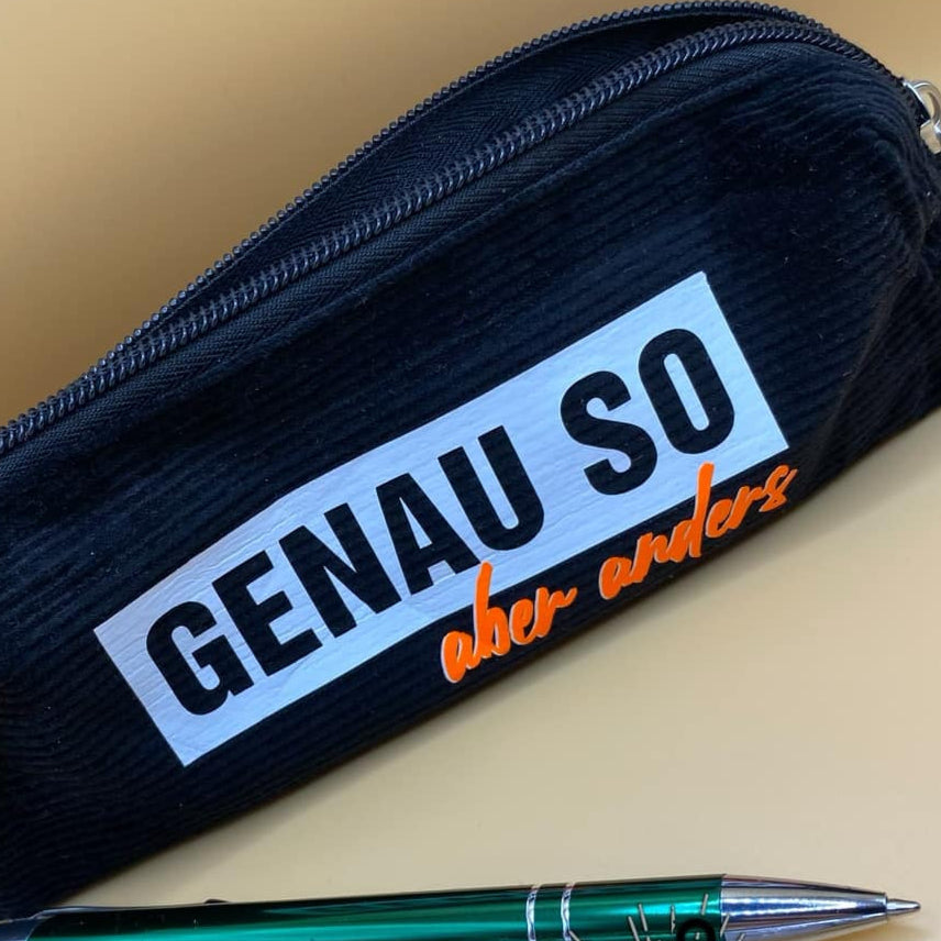Schwarzes Stiftemäppchen mit der Aufschrift "Genauso aber anders" von easy-sticks, gefüllt mit Schreibutensilien, ideal für Schule oder Büro.