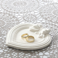 Herz-Bilderrahmen aus Silikon von easy-sticks mit goldenen Trauringen darauf, dekoriert mit einem zarten Schleifenmotiv auf einem eleganten Tisch. Ideal für kreative Designs und persönliche Geschenke.