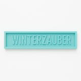 Einfache Silikonform von Easy-Sticks in türkis mit dem Schriftzug WINTERZAUBER, perfekt für einzigartige Weihnachtsdekorationen.
