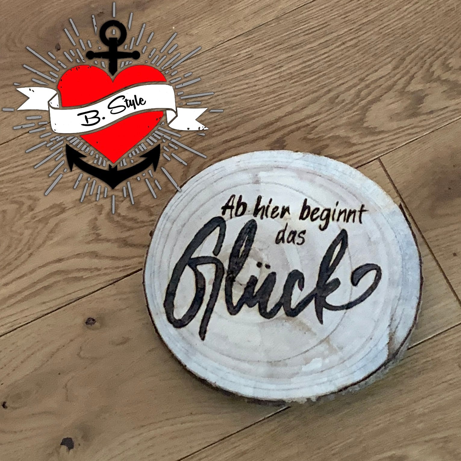 Rustikale Holzscheibe von easy-sticks, die den Schriftzug 'Ab hier beginnt das Glück' in einer eleganten Schriftart zeigt, ideal für dekorative Projekte.