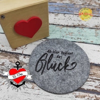 Stylische Filzunterlage von easy-sticks mit dem Aufdruck 'Ab hier beginnt das Glück', kombiniert mit einem charmanten Holzblock.