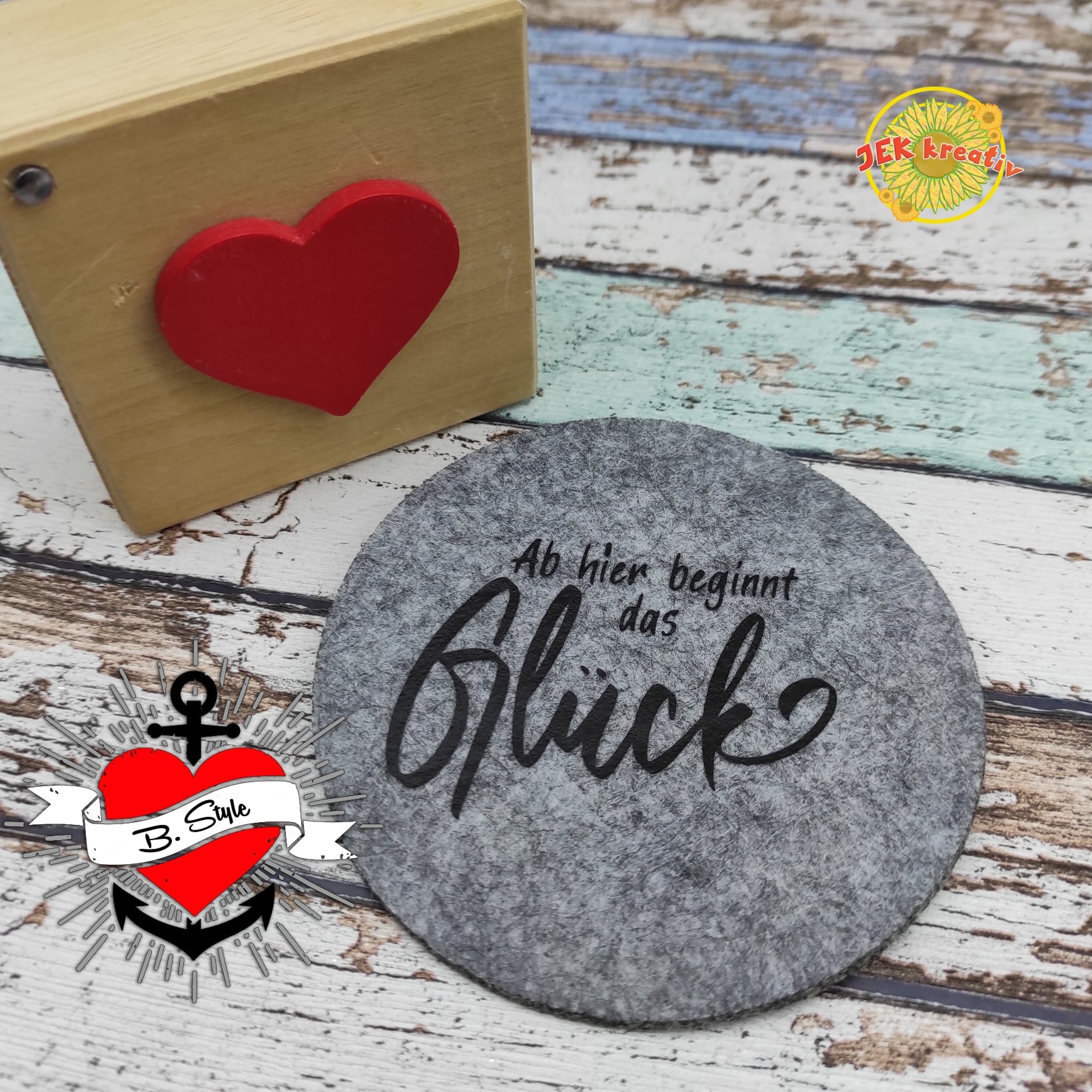 Stylische Filzunterlage von easy-sticks mit dem Aufdruck 'Ab hier beginnt das Glück', kombiniert mit einem charmanten Holzblock.