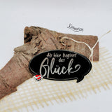Elegantes Acrylschild von easy-sticks mit dem inspirierenden Spruch 'Ab hier beginnt das Glück', dekoriert auf einem rustikalen Holzstück.