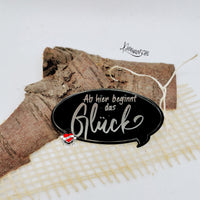 Elegantes Acrylschild von easy-sticks mit dem inspirierenden Spruch 'Ab hier beginnt das Glück', dekoriert auf einem rustikalen Holzstück.
