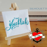 Kreatives Projekt mit der Plotterdatei "Einfach Glücklich sein" von easy-sticks, präsentiert auf einer kleinen Staffelei. Das Design zeigt den inspirierenden Schriftzug "glücklich sein" in stilvollem Türkis und erzeugt eine positive Atmosphäre.