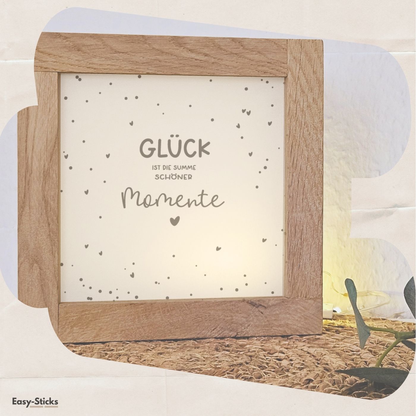 Einfach umgesetzte Lichtbox von easy-sticks, mit dem inspirierenden Spruch 'GLÜCK ist die Summe schöner Momente', umgeben von warmem Licht und dekorativem Rahmen.