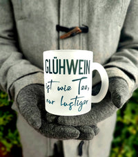 Eine stilvolle Tasse mit dem Spruch "GLÜHWEIN ist wie Tee, nur lustiger" in grünem Schriftzug, perfekt für winterliche Getränke und kreative Projekte von easy-sticks.