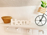 Silikonform von Easy-Sticks mit der Aufschrift 'Home', rustikal präsentiert auf einem Regalsystem zwischen Deko-Elementen.
