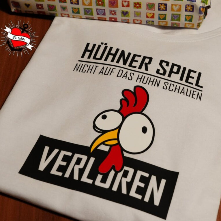 Hühnermotiv auf einem weißen T-Shirt mit dem Schriftzug "HÜHNER SPIEL NICHT AUF DAS Huhn SCHAUEN VERLOREN", ideal für kreative Projekte von easy-sticks.