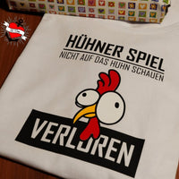 Hühnermotiv auf einem weißen T-Shirt mit dem Schriftzug "HÜHNER SPIEL NICHT AUF DAS Huhn SCHAUEN VERLOREN", ideal für kreative Projekte von easy-sticks.