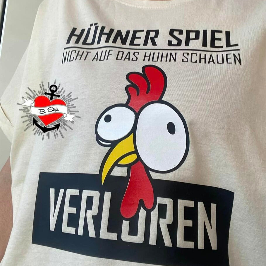 T-Shirt mit dem Motiv "Hühner Spiel" von easy-sticks, Features einen witzigen Huhn-Print und den Slogan "VERLORREN".