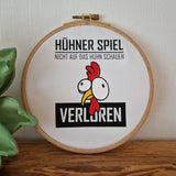 Originelles Stickbild des Hühner Spiels von easy-sticks, das ein charakteristisches Hühner-Motiv zeigt mit dem Spruch "Nicht auf das Huhn schauen - Verloren" in einem hübschen Holzrahmen.