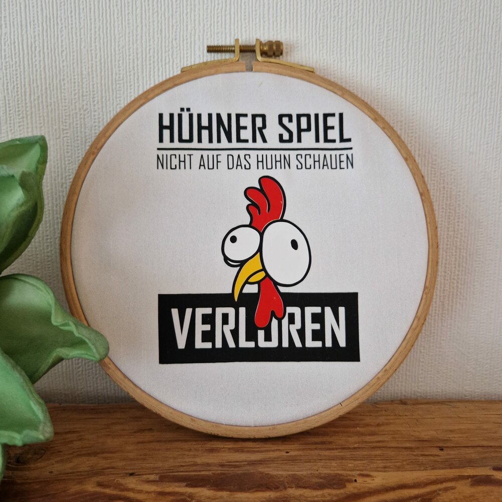 Originelles Stickbild des Hühner Spiels von easy-sticks, das ein charakteristisches Hühner-Motiv zeigt mit dem Spruch "Nicht auf das Huhn schauen - Verloren" in einem hübschen Holzrahmen.