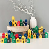 Bunte Miniaturhäuser aus Holz in verschiedenen Farben, dekoriert und präsentiert mit Easy-Sticks Acryl Creme von Easy-Sticks.