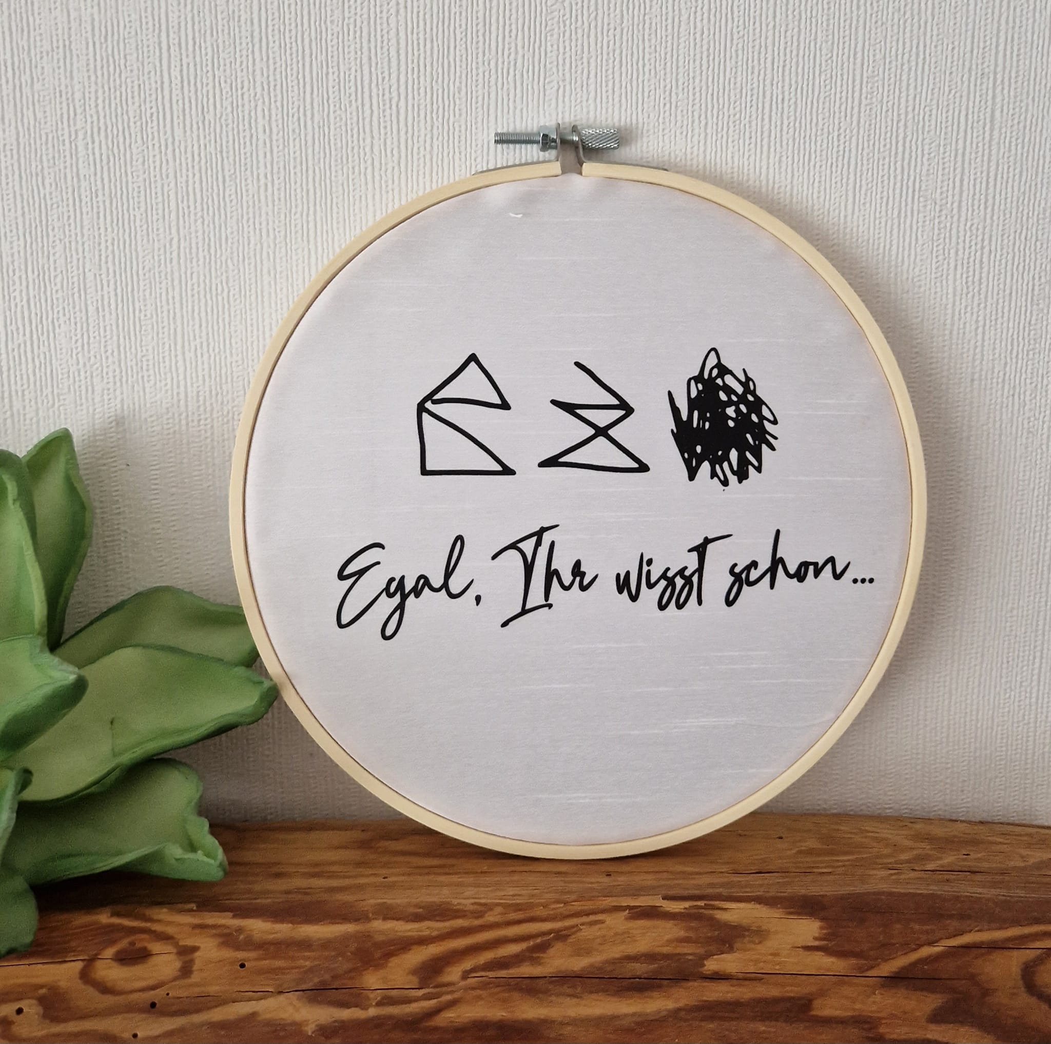 Ansprechendes Stickrahmenkreativprojekt mit minimalistischen grafischen Elementen und dem Spruch 'Egal, Ihr wisst schon...'. Ideal für persönliche DIY-Projekte mit der Haus vom Nikolaus Plotterdatei von easy-sticks.