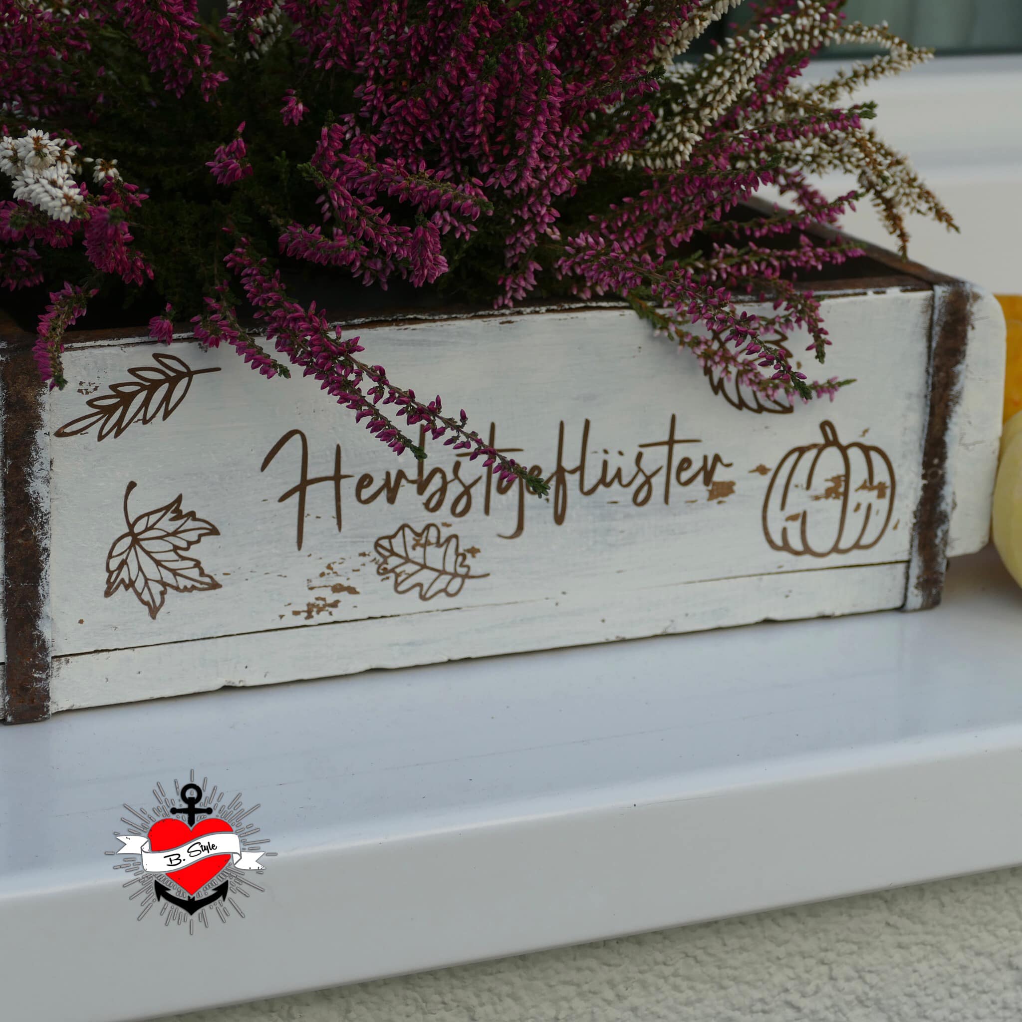 Stilvolles Blütenarrangement in einer Holzbox mit der Aufschrift 'Herbstgeflüster', perfekt für die Herbstdekoration. Herbstdiy Sprüche für den Plotter und in PDF zum Ausdrucken auf Wasserschiebefolie von easy-sticks.