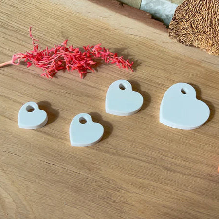 Vier wunderschöne Silikonherzen von Easy-Sticks zum Aufhängen auf einem Holzuntergrund, perfekt für kreative Bastelideen.