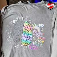 Hirn Plotterdatei von easy-sticks auf einem grauen T-Shirt, das ein farbenfrohes, kreatives Gehirn-Design zeigt, umgeben von wissenschaftlichen Symbolen und künstlerischen Elementen.