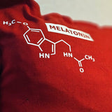 Ein rotes Kissen mit der chemischen Struktur von Melatonin, dekorativ designt von easy-sticks im Zusammenhang mit der Plotterdatei 'Hormone Zeichen'.