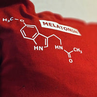 Ein rotes Kissen mit der chemischen Struktur von Melatonin, dekorativ designt von easy-sticks im Zusammenhang mit der Plotterdatei 'Hormone Zeichen'.