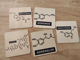 Holzuntersetzer mit chemischen Formeln für Hormone, präsentiert in einem ansprechenden Design, erhältlich in der Plotter Datei 'Hormone Zeichen' von easy-sticks.