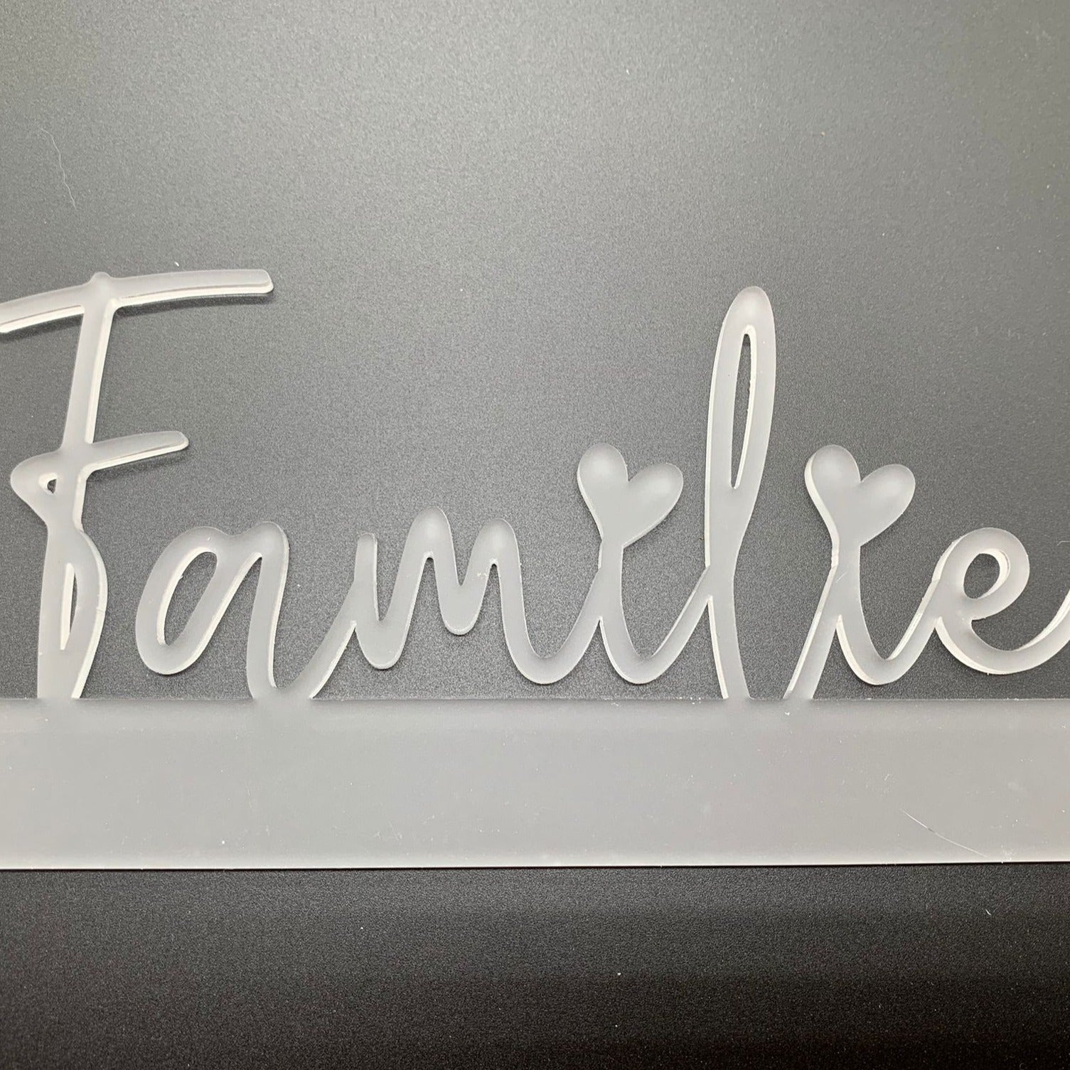 Nahaufnahme des satinierte Acryl Aufstellers 'Familie' von Easy-Sticks, mit Herzchen-Design, elegant vor einem grauen Hintergrund.