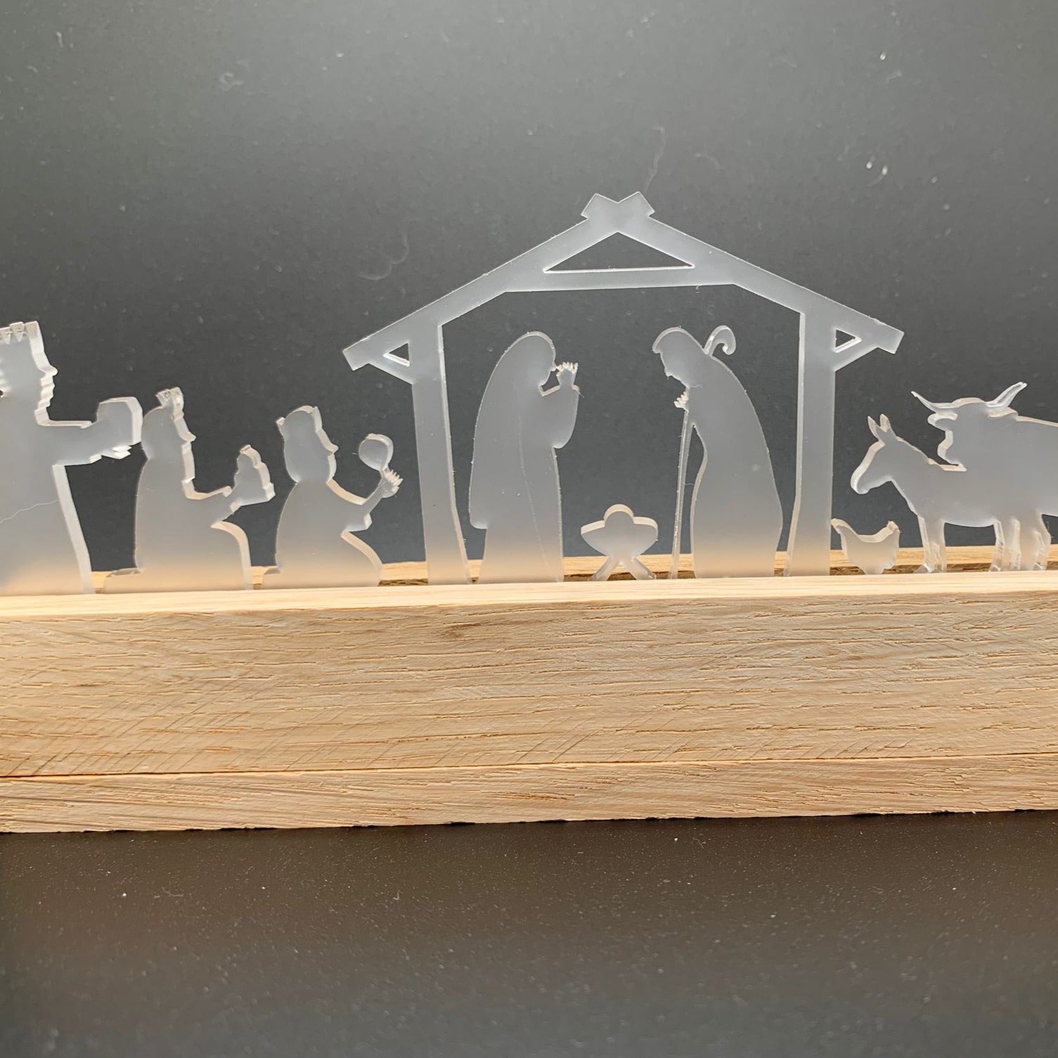 Stilvolle Krippe satiniert von Easy-Sticks, zeigt die Geburt Jesus mit detaillierten Figuren und Holzsockel. Perfekt für festliche Dekoration.