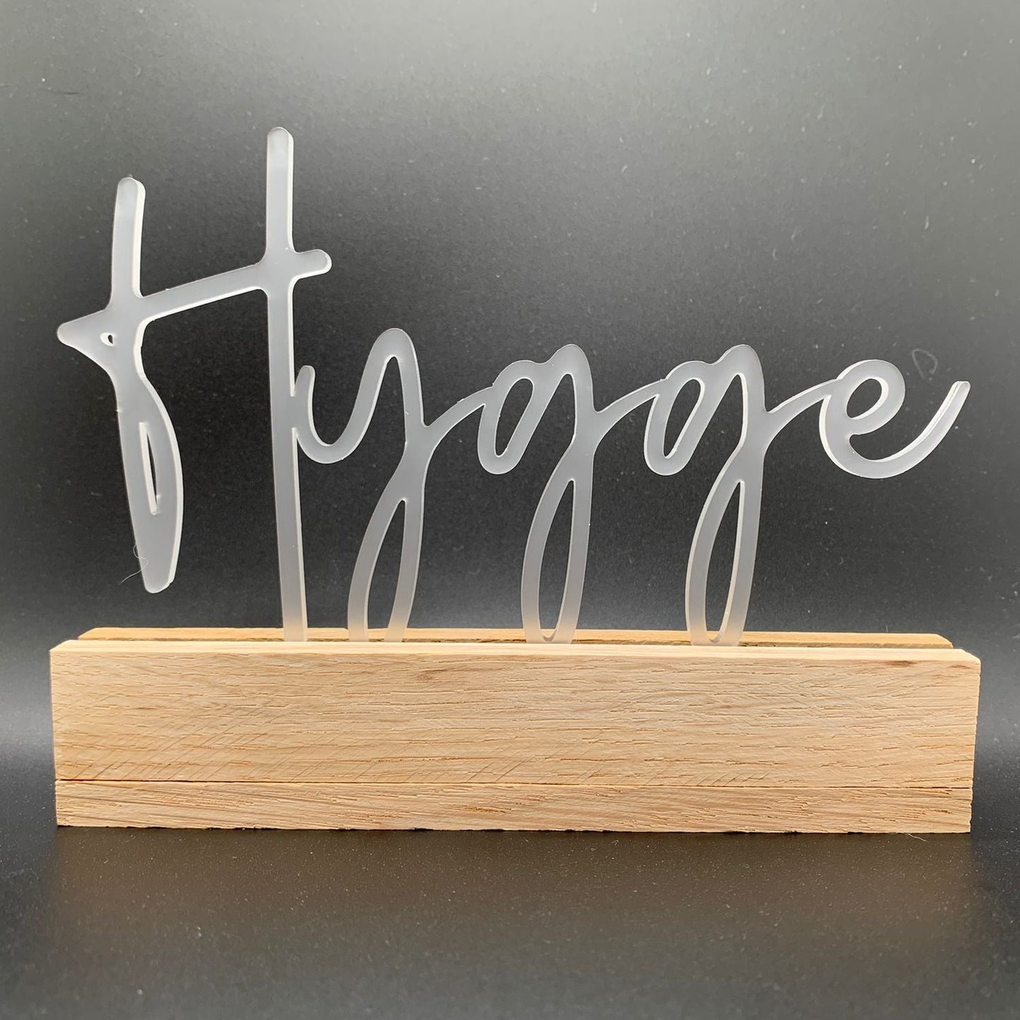 Elegant Hygge Schriftzug in transparenter Acryl-Optik auf Holzsockel, ideal für Dekorationen von Easy-Sticks. Perfekt für ein stilvolles Zuhause - Easy-Sticks Acryl Aufsteller - Hygge.